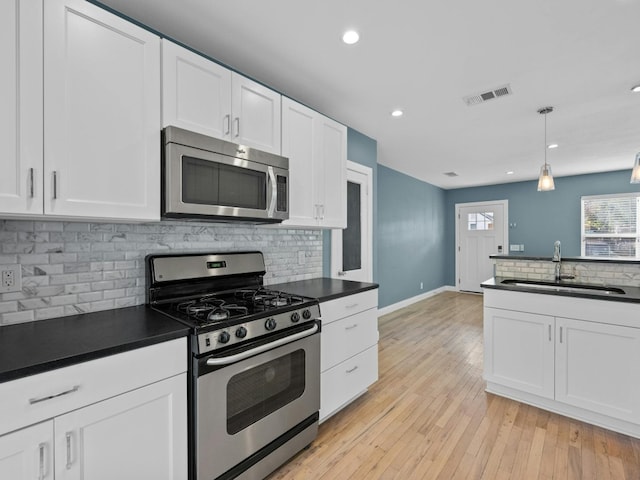 kitchen featuring sink, hanging light fixtures, backsplash, white cabinets, and appliances with stainless steel finishes