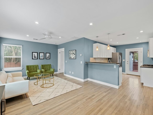 living room with ceiling fan, plenty of natural light, and light wood-type flooring