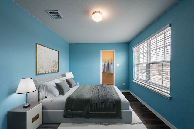 bedroom with a spacious closet, dark wood-type flooring, and a closet