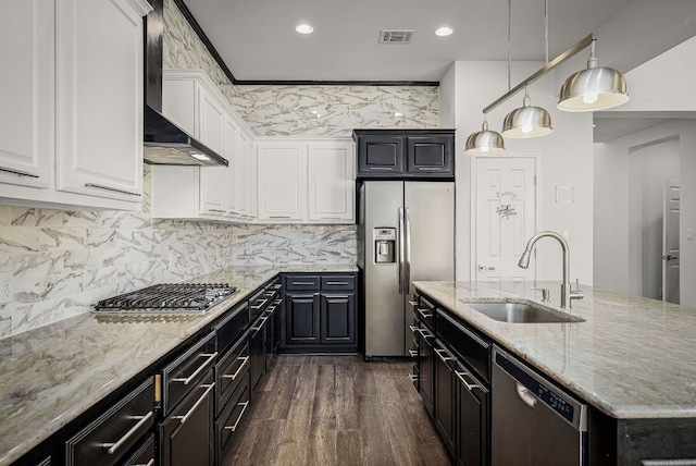 kitchen with wall chimney exhaust hood, sink, stainless steel appliances, light stone countertops, and white cabinets