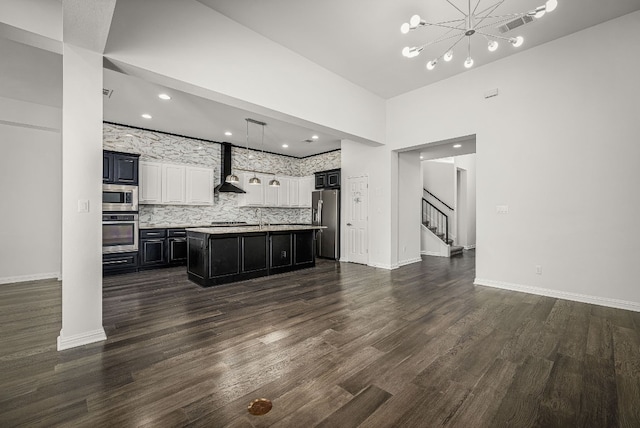 kitchen featuring appliances with stainless steel finishes, backsplash, dark hardwood / wood-style floors, a center island with sink, and wall chimney exhaust hood