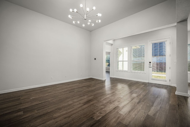 spare room with an inviting chandelier and dark hardwood / wood-style flooring