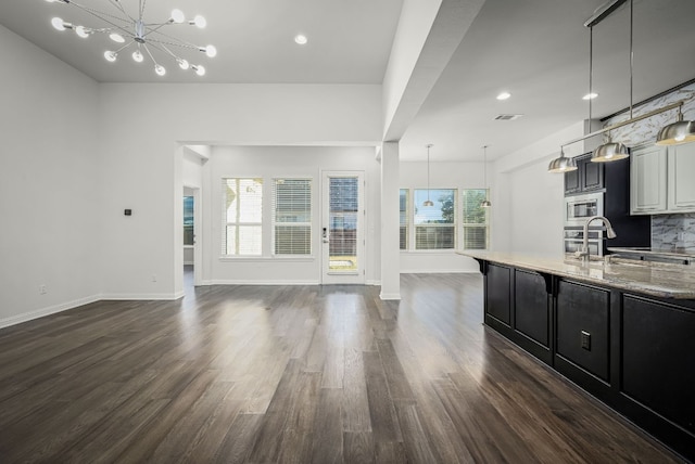 unfurnished living room with a notable chandelier, sink, and dark hardwood / wood-style floors