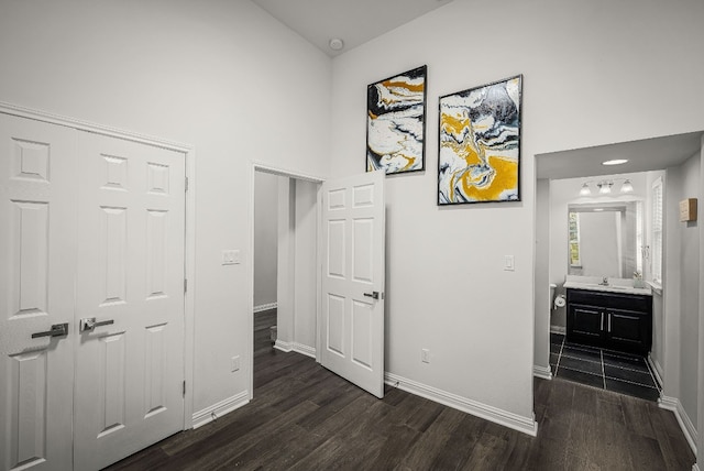 corridor with dark hardwood / wood-style floors, sink, and high vaulted ceiling