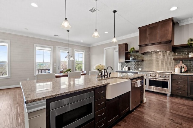 kitchen with backsplash, dark hardwood / wood-style flooring, a center island with sink, and appliances with stainless steel finishes