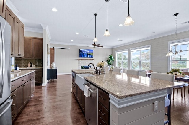 kitchen with a kitchen breakfast bar, appliances with stainless steel finishes, sink, a barn door, and an island with sink