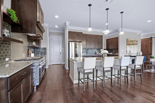 kitchen with backsplash, a barn door, stainless steel appliances, and decorative light fixtures