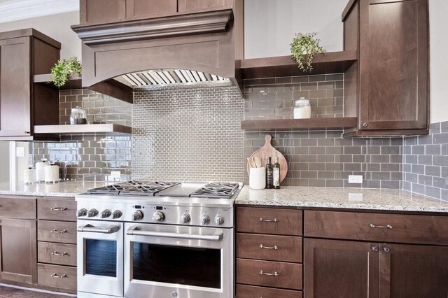 kitchen featuring light stone counters, premium range hood, backsplash, and stainless steel stove