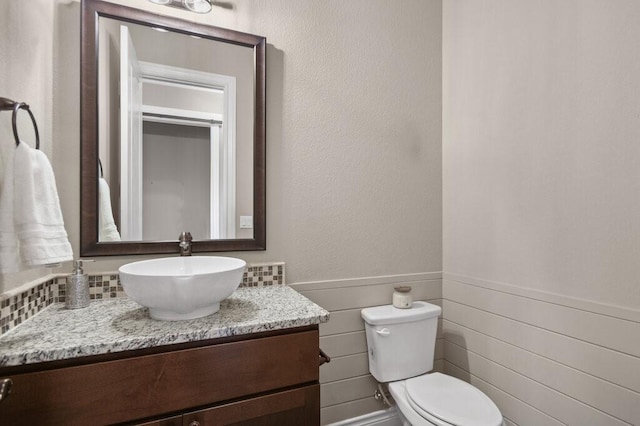 bathroom with vanity, toilet, and tile walls