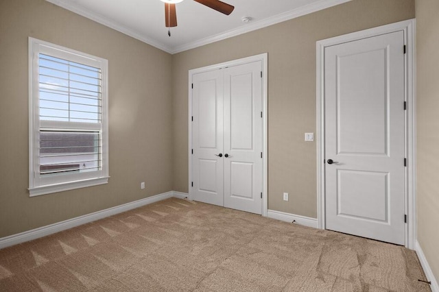 unfurnished bedroom featuring ceiling fan, crown molding, and light colored carpet