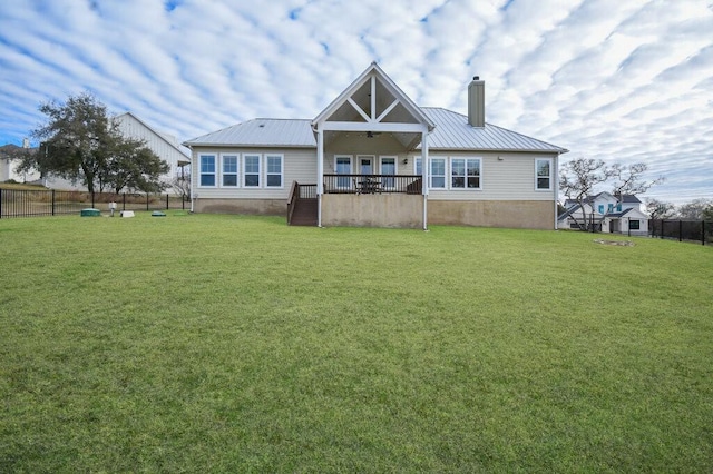 rear view of house with ceiling fan and a yard