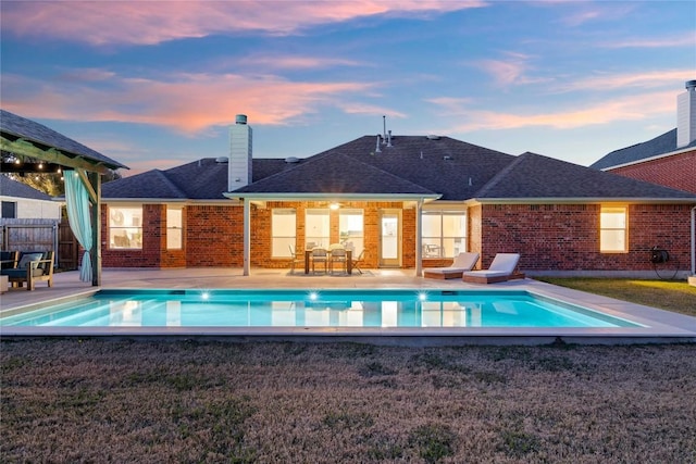 pool at dusk with a patio area