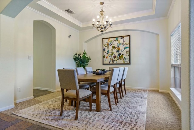 dining area featuring carpet flooring, crown molding, a tray ceiling, and an inviting chandelier