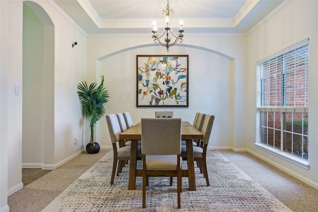 dining area with carpet floors, a tray ceiling, and a notable chandelier