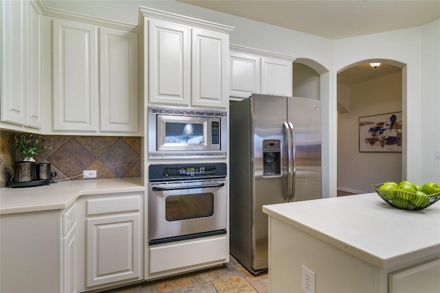 kitchen with tasteful backsplash, white cabinets, and appliances with stainless steel finishes