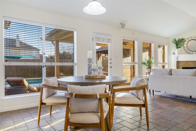 sunroom with vaulted ceiling, a wealth of natural light, and a tiled fireplace