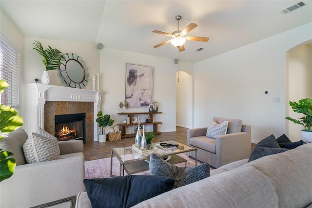 living room with a tiled fireplace and ceiling fan