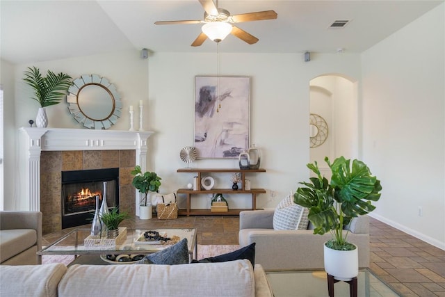 living room featuring ceiling fan and a tiled fireplace