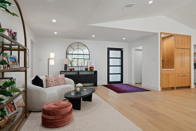 living room featuring vaulted ceiling and light hardwood / wood-style flooring