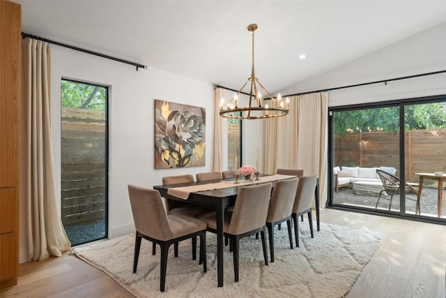 dining room featuring a chandelier, vaulted ceiling, and light wood-type flooring