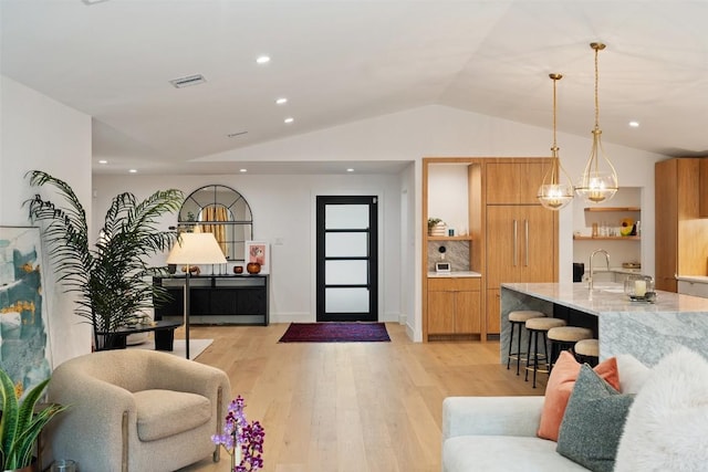 living room with light hardwood / wood-style flooring, a chandelier, lofted ceiling, and sink