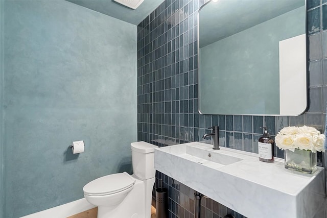 bathroom featuring sink, tile walls, and toilet