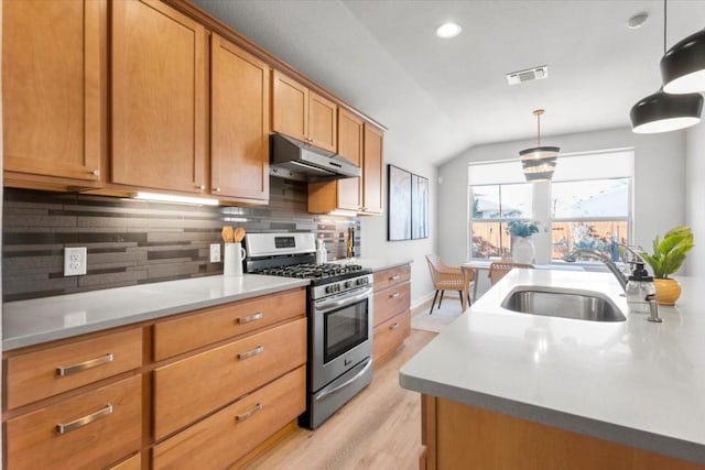 kitchen featuring backsplash, vaulted ceiling, sink, stainless steel range with gas cooktop, and hanging light fixtures