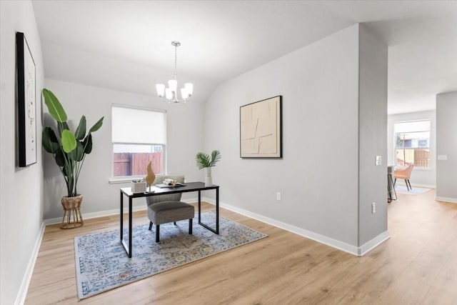 home office with a chandelier, vaulted ceiling, and light wood-type flooring