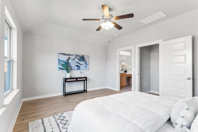 bedroom with multiple windows, ensuite bathroom, ceiling fan, and hardwood / wood-style flooring