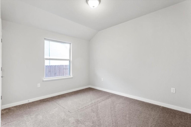 carpeted spare room with vaulted ceiling