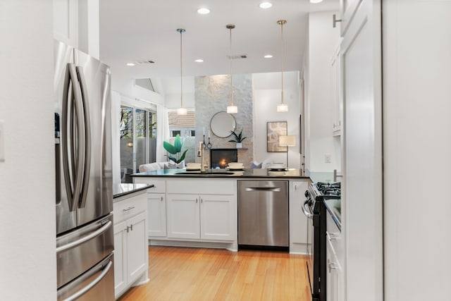 kitchen featuring white cabinetry, sink, decorative light fixtures, and appliances with stainless steel finishes