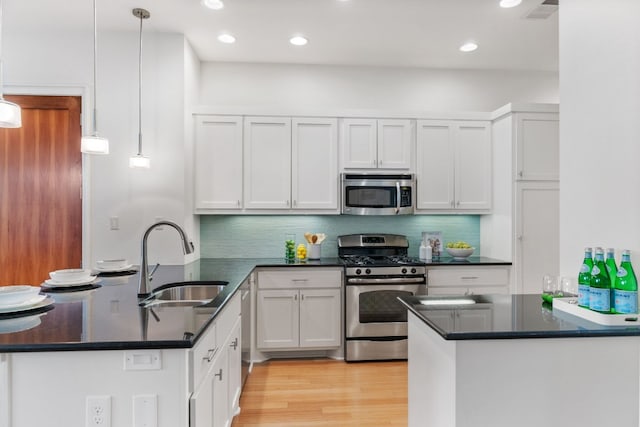 kitchen with stainless steel appliances, white cabinetry, hanging light fixtures, and sink