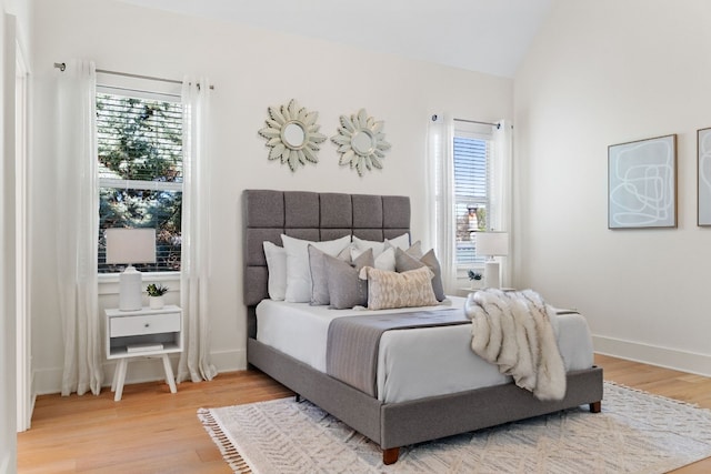 bedroom featuring multiple windows, hardwood / wood-style floors, and lofted ceiling