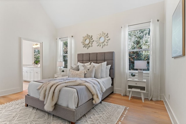 bedroom featuring hardwood / wood-style floors, ensuite bath, and lofted ceiling