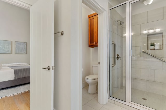 bathroom with tile patterned floors, toilet, and a shower with door