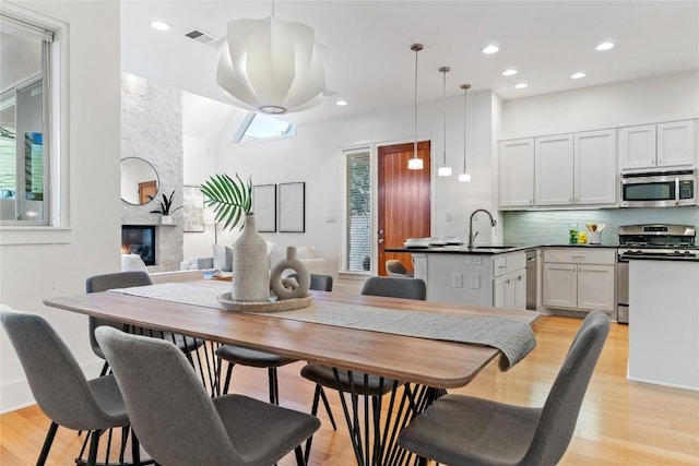 dining area with light hardwood / wood-style floors, a fireplace, a healthy amount of sunlight, and sink