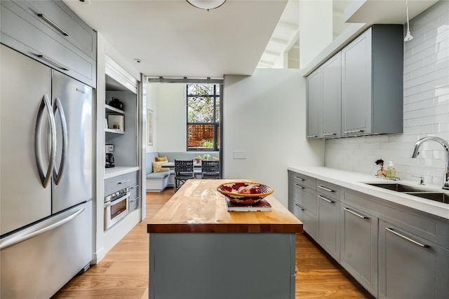 kitchen with wooden counters, appliances with stainless steel finishes, tasteful backsplash, gray cabinetry, and sink