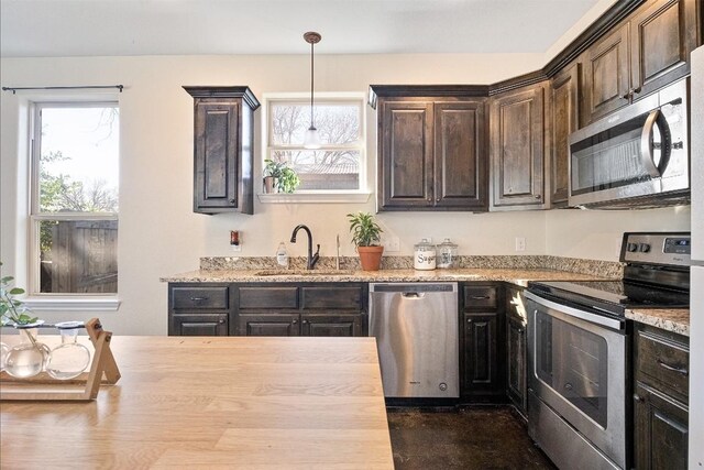 kitchen with sink, butcher block countertops, hanging light fixtures, stainless steel appliances, and dark brown cabinetry