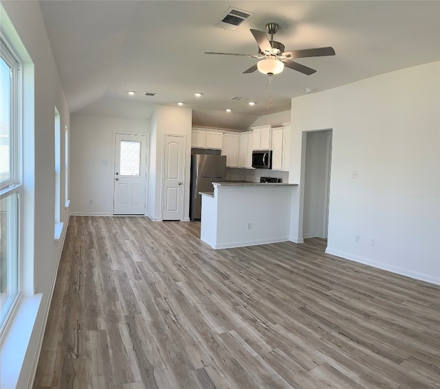 kitchen featuring stainless steel appliances, vaulted ceiling, ceiling fan, white cabinets, and light hardwood / wood-style floors