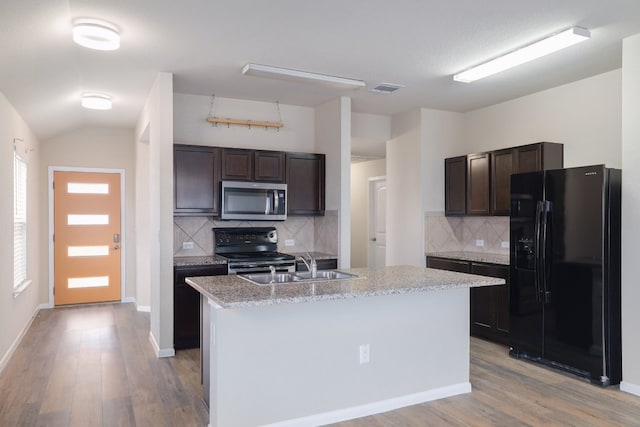 12110 Riprap Dr, Manor, TX 78653 - kitchen with black appliances, light wood-type flooring, dark brown cabinetry, and vaulted ceiling