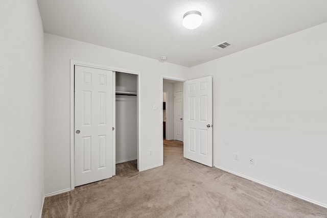 unfurnished bedroom featuring light colored carpet and a closet