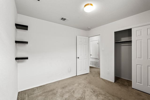 unfurnished bedroom with light carpet, a textured ceiling, and a closet