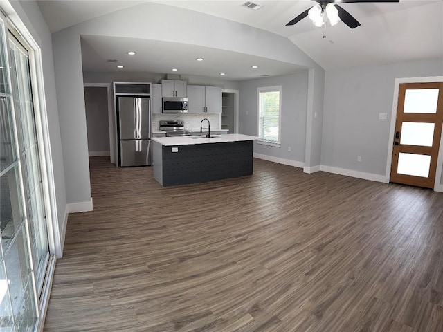 kitchen with a kitchen island with sink, sink, vaulted ceiling, tasteful backsplash, and stainless steel appliances