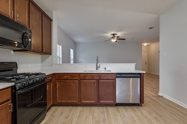 kitchen featuring kitchen peninsula, light wood-type flooring, sink, and black appliances