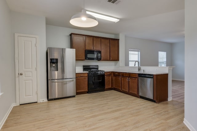 kitchen featuring sink, light wood-type flooring, kitchen peninsula, and black appliances