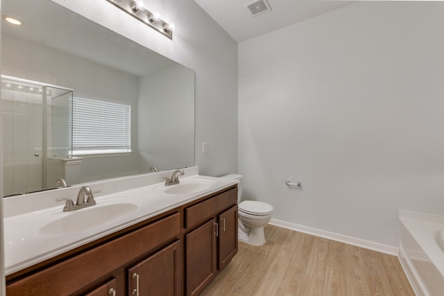 full bathroom with wood-type flooring, vanity, shower with separate bathtub, and toilet