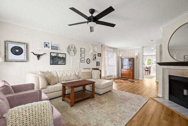 living room with ceiling fan, light hardwood / wood-style floors, and ornamental molding