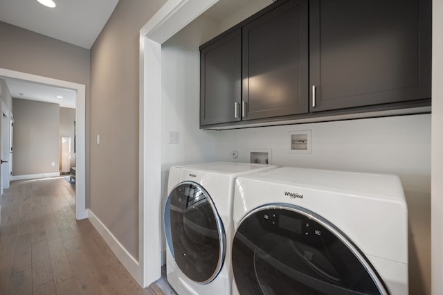 clothes washing area featuring separate washer and dryer, cabinets, and light hardwood / wood-style floors