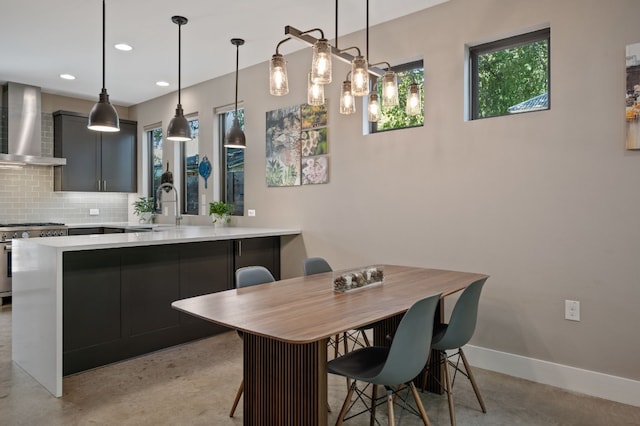 kitchen featuring pendant lighting, wall chimney exhaust hood, stainless steel range, tasteful backsplash, and kitchen peninsula