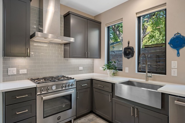 kitchen with wall chimney range hood, sink, gray cabinets, stainless steel appliances, and tasteful backsplash